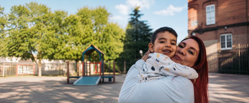 A happy mother and son smiling at a playground, reflecting the safe environment provided for families by Operation HOPE-North County.
