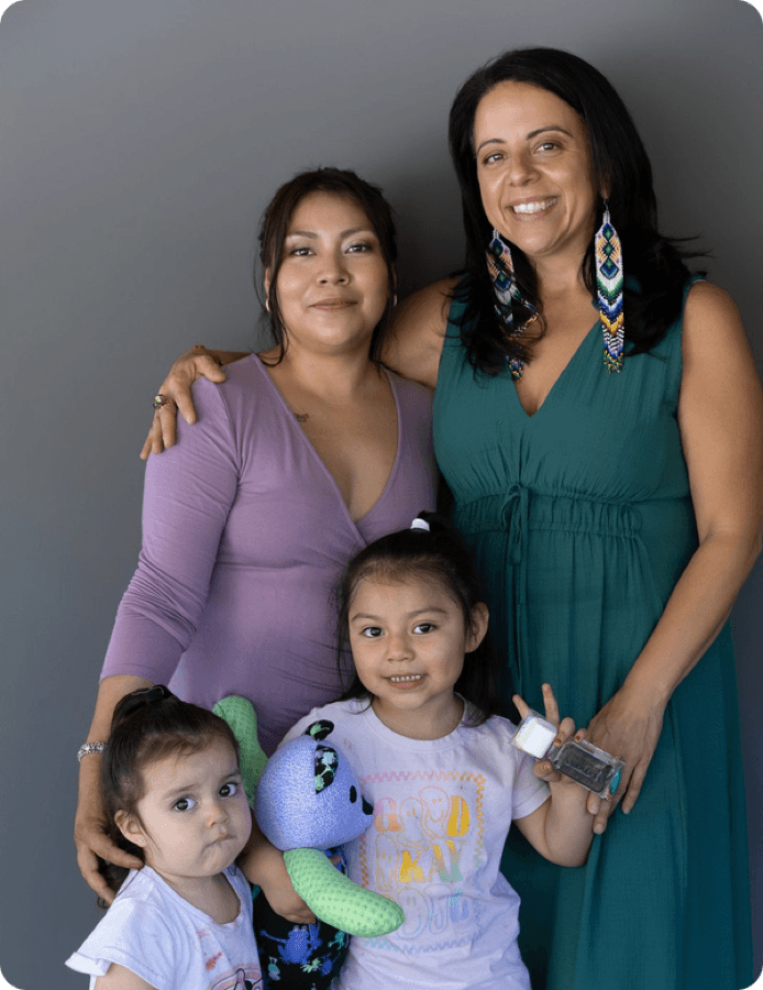 Two women and two young children smiling together.
