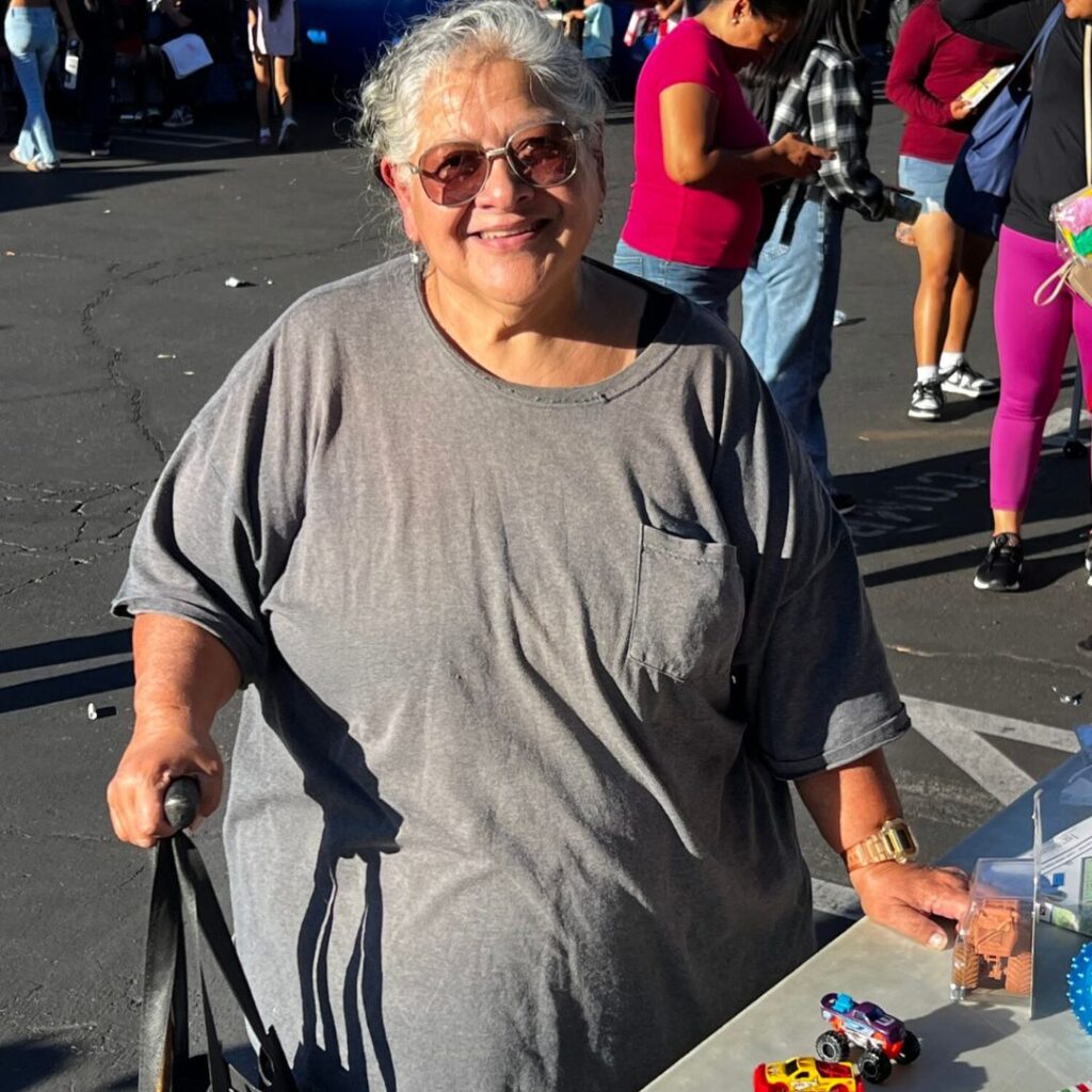 A smiling older woman with grey hair and sunglasses.